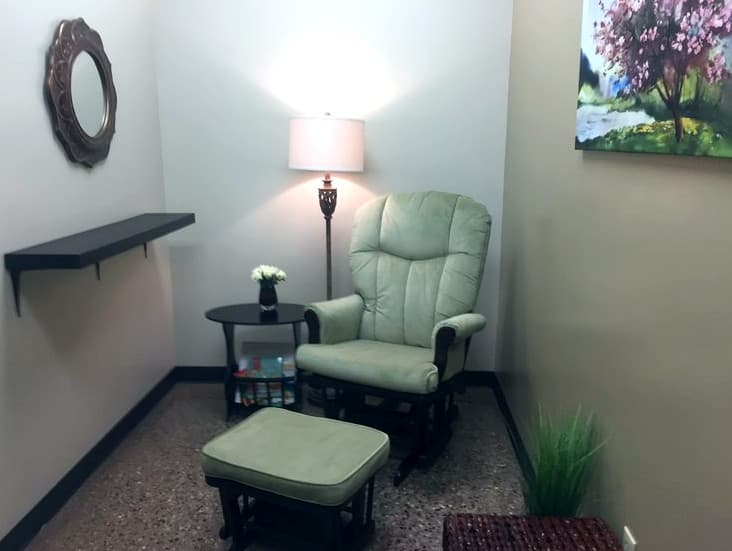 A Mother's Room with a glider chair, ottoman, warm lamp, and children's books nearby
